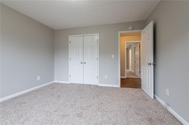 unfurnished bedroom with light colored carpet, a textured ceiling, and a closet