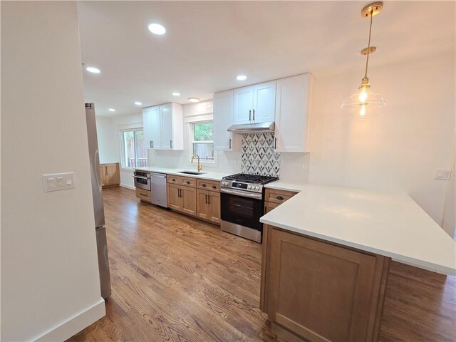 kitchen with pendant lighting, light wood-type flooring, white cabinetry, kitchen peninsula, and stainless steel appliances