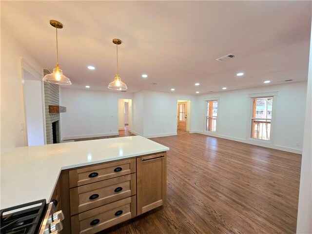 kitchen featuring dark hardwood / wood-style floors, hanging light fixtures, and a brick fireplace