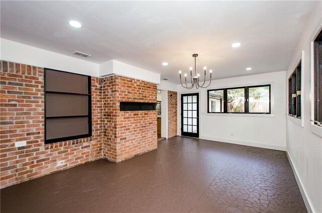 unfurnished living room featuring brick wall and an inviting chandelier