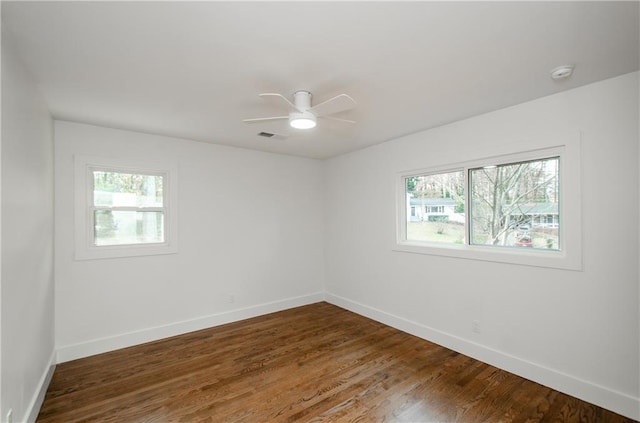 spare room with plenty of natural light, ceiling fan, and dark wood-type flooring