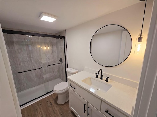 bathroom with toilet, vanity, a shower with shower door, and hardwood / wood-style flooring