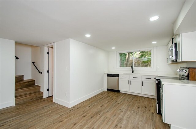 kitchen with white cabinetry, sink, light hardwood / wood-style floors, and appliances with stainless steel finishes