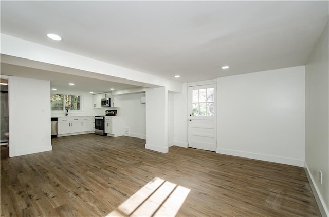 unfurnished living room with wood-type flooring, a healthy amount of sunlight, and sink