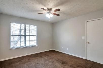 unfurnished room featuring ceiling fan, dark carpet, and a textured ceiling