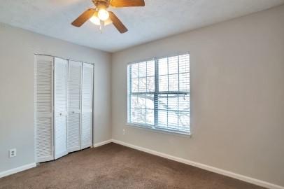 carpeted empty room with ceiling fan and a textured ceiling