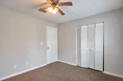 unfurnished bedroom featuring ceiling fan, dark carpet, and a closet