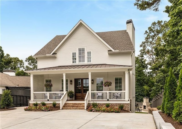 view of front of house with a standing seam roof, a chimney, covered porch, and metal roof
