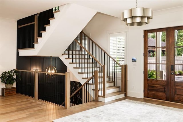 foyer entrance with french doors, baseboards, an inviting chandelier, wood finished floors, and stairway