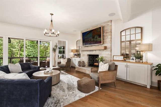 living area with beamed ceiling, wood finished floors, a stone fireplace, and a chandelier