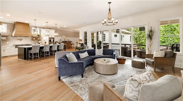 living area featuring light wood finished floors, an inviting chandelier, recessed lighting, and crown molding