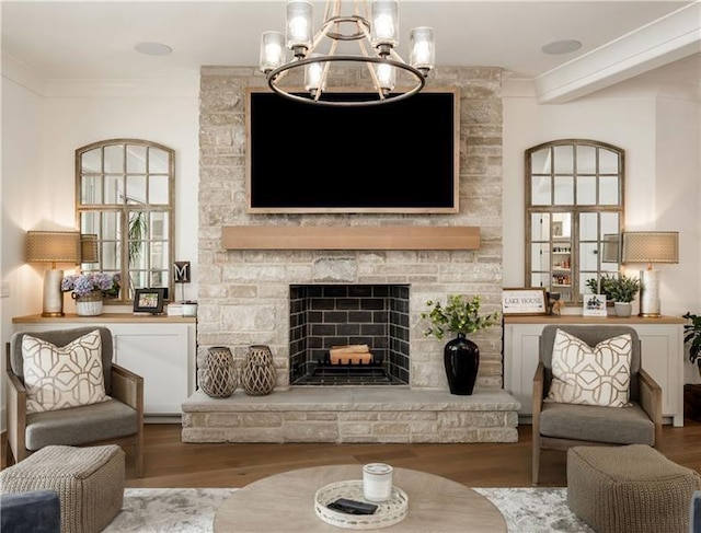 living area featuring a stone fireplace, crown molding, and wood finished floors
