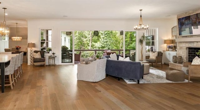 living room featuring wood finished floors, a stone fireplace, and a notable chandelier