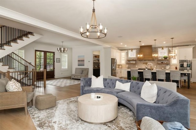 living area featuring stairway, a chandelier, and light wood-style floors