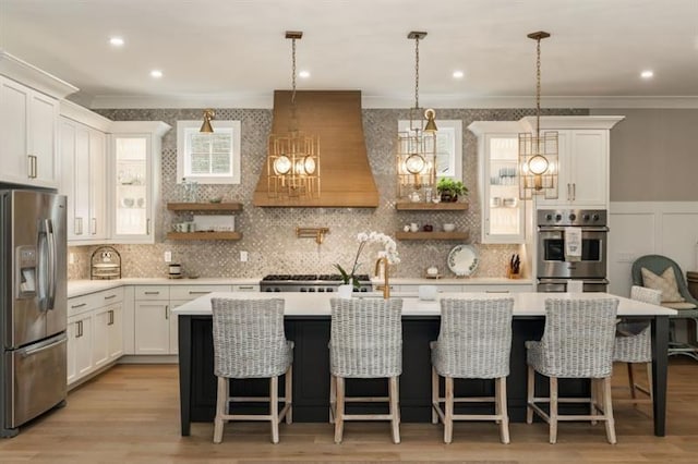 kitchen with light countertops, custom exhaust hood, ornamental molding, and appliances with stainless steel finishes