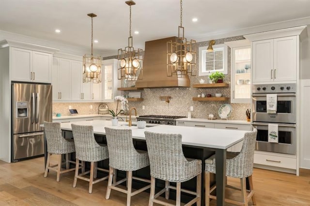 kitchen with custom exhaust hood, appliances with stainless steel finishes, white cabinetry, and light countertops