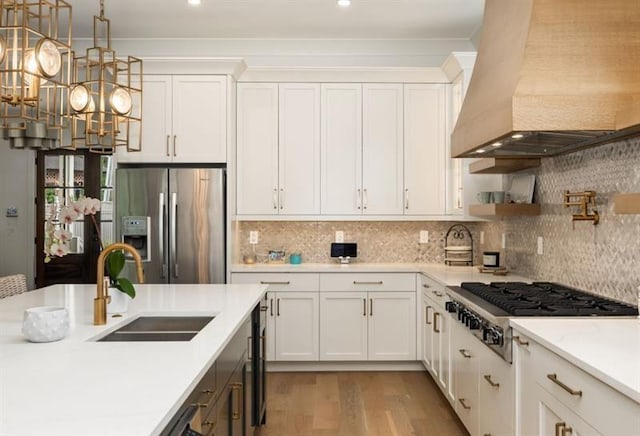 kitchen featuring white cabinets, stainless steel appliances, light countertops, a sink, and premium range hood