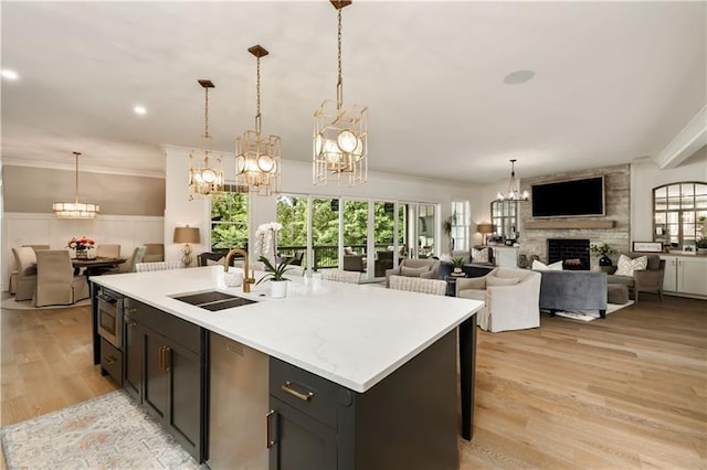 kitchen with open floor plan, an inviting chandelier, light countertops, a sink, and a large fireplace