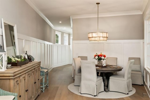 dining space featuring a decorative wall, crown molding, a wainscoted wall, and wood finished floors