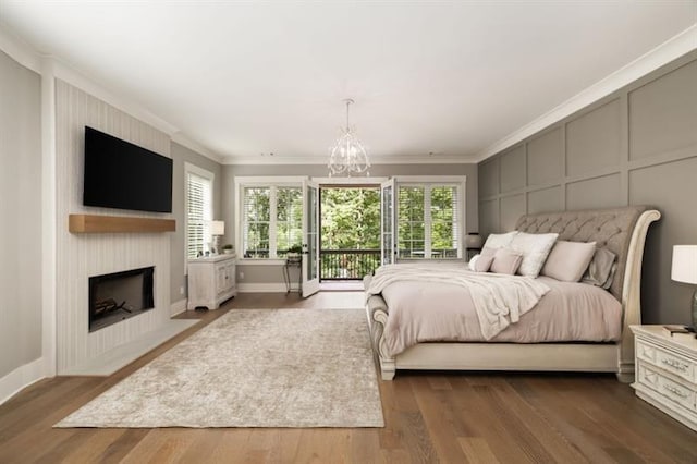 bedroom featuring a decorative wall, a large fireplace, ornamental molding, and an inviting chandelier