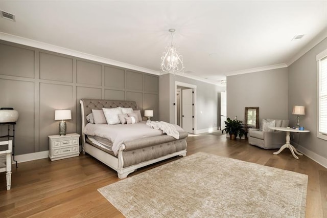bedroom with visible vents, a chandelier, wood finished floors, a decorative wall, and ornamental molding