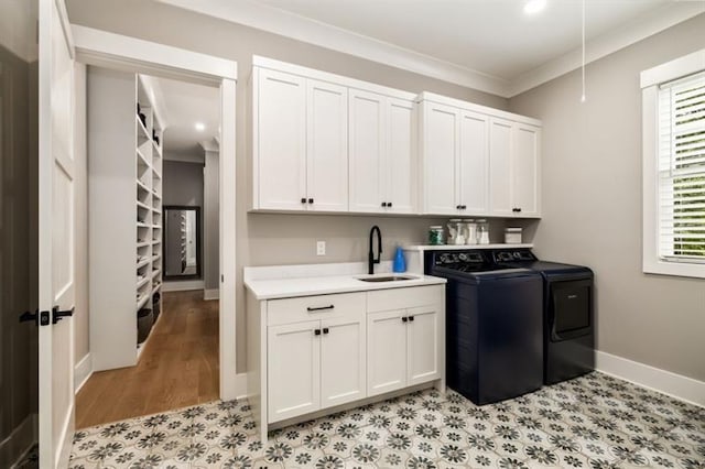 laundry room with a sink, baseboards, cabinet space, crown molding, and washer and dryer