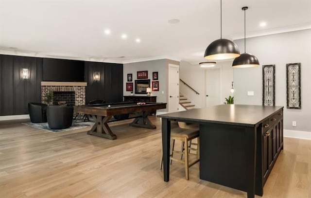 interior space with dark cabinetry, light wood-type flooring, crown molding, baseboards, and a fireplace