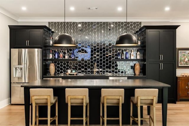 bar featuring indoor wet bar, light wood finished floors, a sink, and stainless steel fridge with ice dispenser