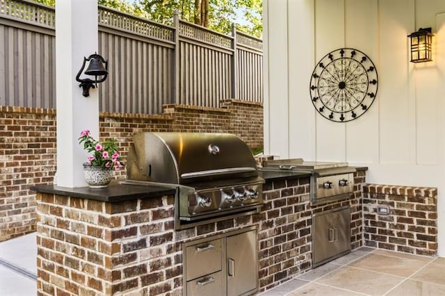 view of patio with fence, exterior kitchen, and a grill