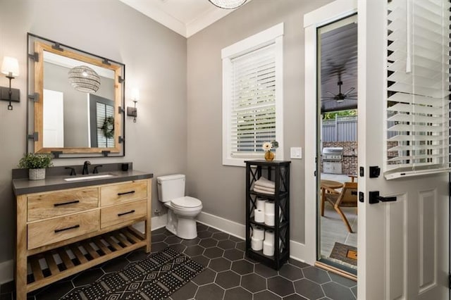 half bath featuring crown molding, vanity, baseboards, toilet, and tile patterned flooring