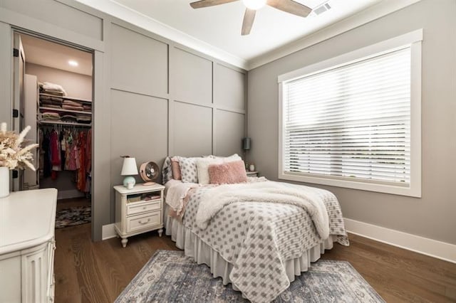 bedroom with a closet, a spacious closet, baseboards, dark wood-style flooring, and visible vents