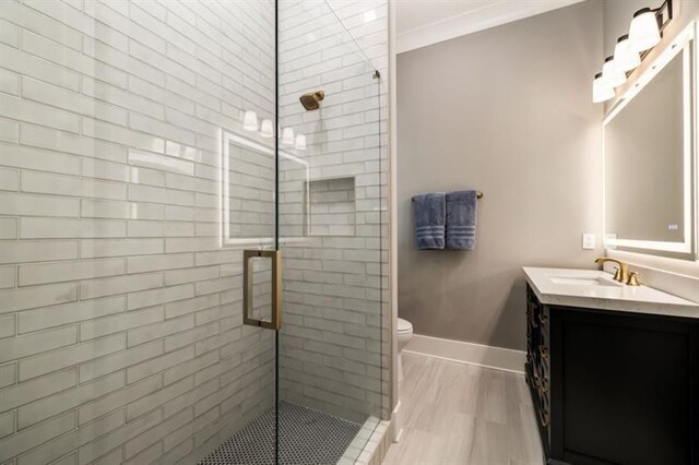 bathroom featuring toilet, a stall shower, baseboards, crown molding, and vanity