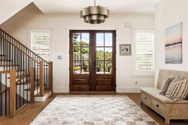 doorway with wood finished floors, an inviting chandelier, french doors, baseboards, and ornamental molding