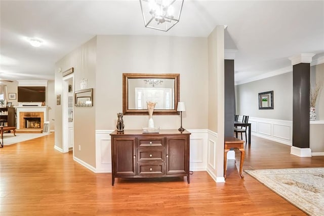 hallway with a notable chandelier, light wood-type flooring, and crown molding