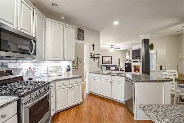 kitchen featuring stone counters, white cabinets, sink, light hardwood / wood-style floors, and stainless steel appliances