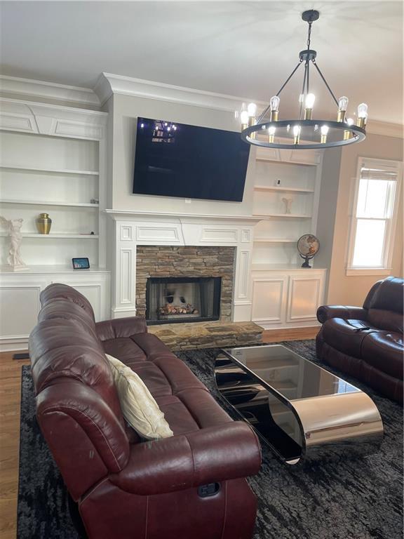 103 Mill Park Chase, Woodstock, GA 30188 - living area with ornamental molding, wood finished floors, a chandelier, a fireplace, and built in features