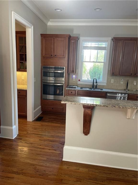 103 Mill Park Chase, Woodstock, GA 30188 - kitchen with appliances with stainless steel finishes, backsplash, a breakfast bar, light stone counters, and dark wood-style flooring