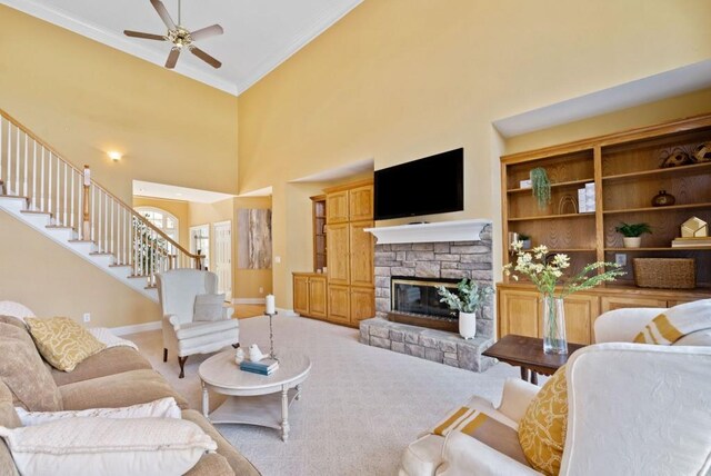 living room featuring crown molding, ceiling fan, a fireplace, light colored carpet, and french doors