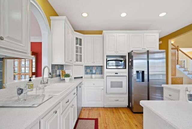 kitchen featuring dishwasher, white cabinetry, light hardwood / wood-style floors, a kitchen island, and white gas cooktop