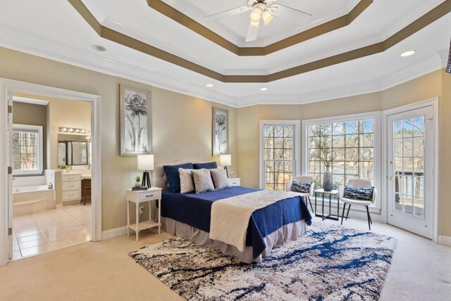 carpeted bedroom featuring connected bathroom, ornamental molding, a tray ceiling, ceiling fan, and access to exterior