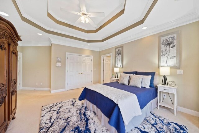 bedroom featuring crown molding, ceiling fan, a raised ceiling, light carpet, and a closet