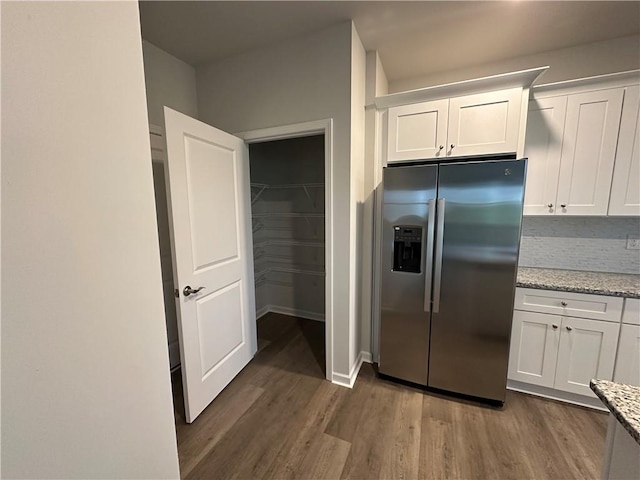 kitchen with white cabinets, stainless steel refrigerator with ice dispenser, light stone counters, and dark hardwood / wood-style flooring