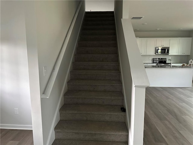 stairs featuring hardwood / wood-style flooring and sink