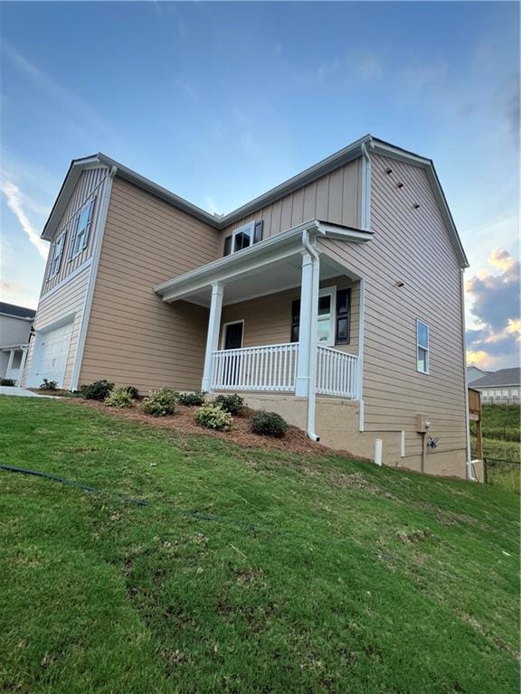 view of front of house with a garage, a front yard, and covered porch