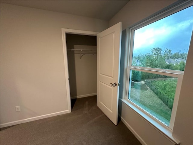 unfurnished bedroom with dark carpet and a closet