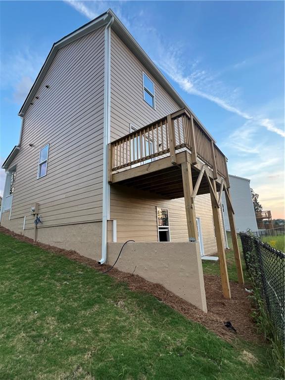 back house at dusk featuring a lawn and a wooden deck