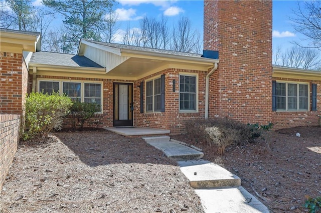 property entrance featuring a chimney and brick siding