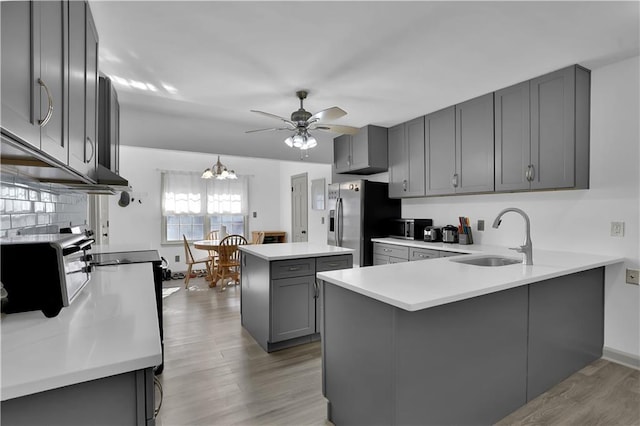 kitchen with gray cabinetry, a sink, a center island, light wood-type flooring, and stainless steel fridge with ice dispenser