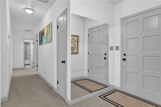 foyer entrance with light carpet, visible vents, and baseboards