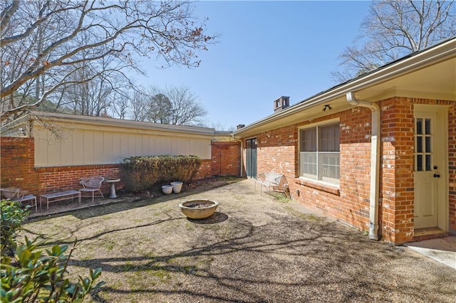 exterior space featuring a patio area, a fire pit, and brick siding